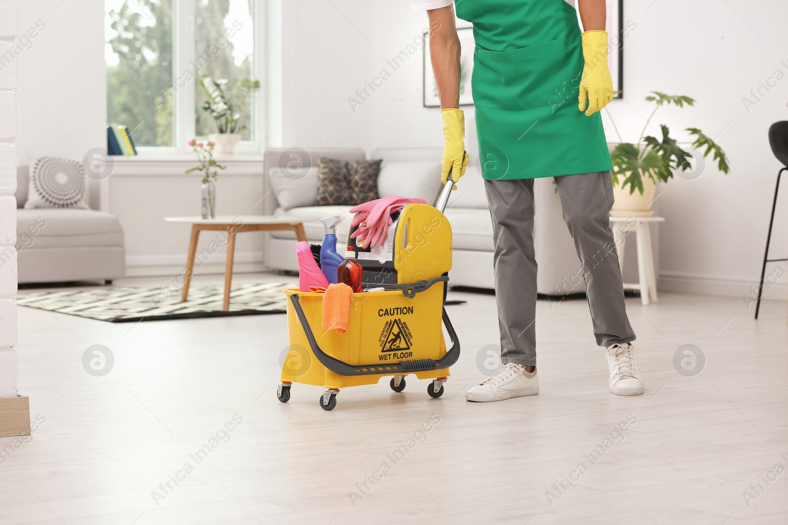 Photo of Man in uniform with cleaning supplies indoors