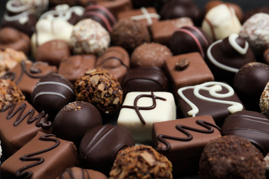 Photo of Different delicious chocolate candies as background, closeup