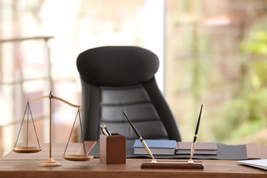 Photo of Table with scales of justice in lawyer's office