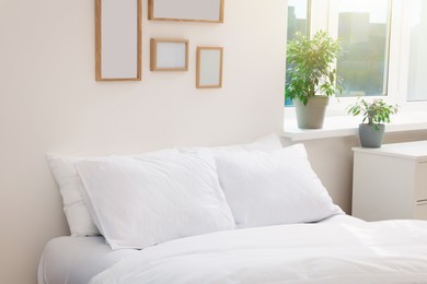 Photo of White soft pillows on cozy bed in room