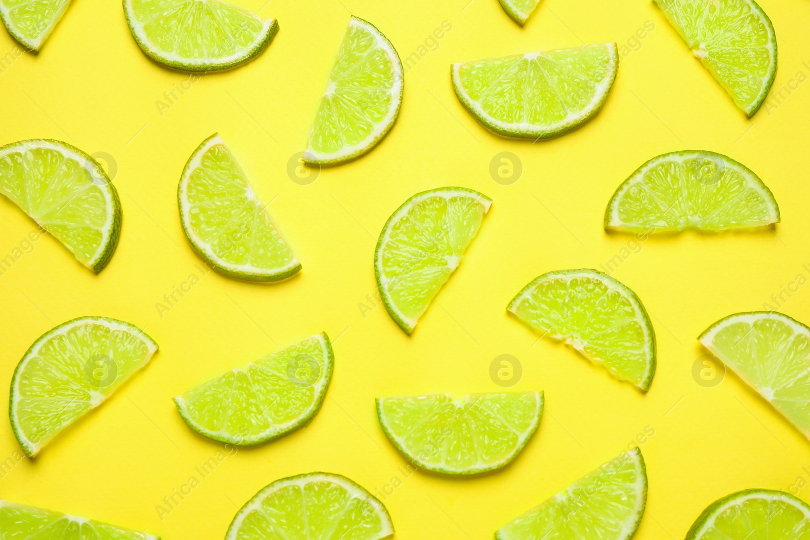 Photo of Juicy fresh lime slices on yellow background, flat lay