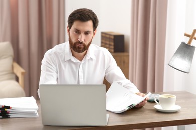 Photo of Businessman working with documents at wooden table in office