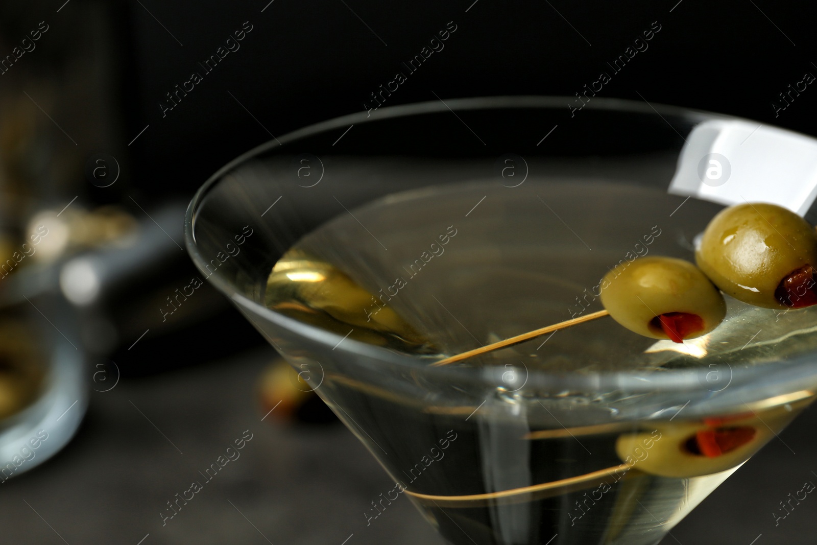 Photo of Glass of Classic Dry Martini with olives on table, closeup