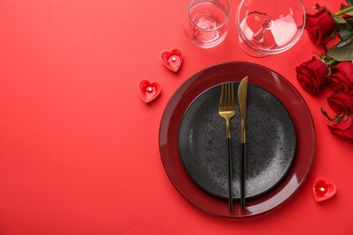 Place setting with heart shaped candles and bouquet of roses for romantic dinner on red table, flat lay. Space for text