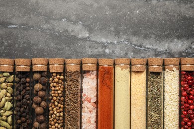 Photo of Glass tubes with different spices on grey marble table, flat lay. Space for text