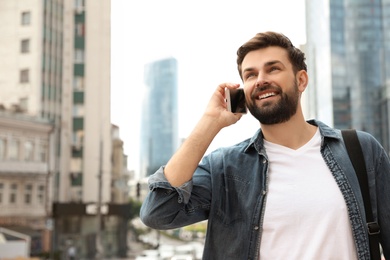 Photo of Handsome man talking on phone in modern city