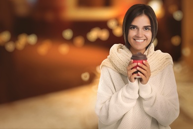 Happy beautiful woman with paper cup of mulled wine outdoors