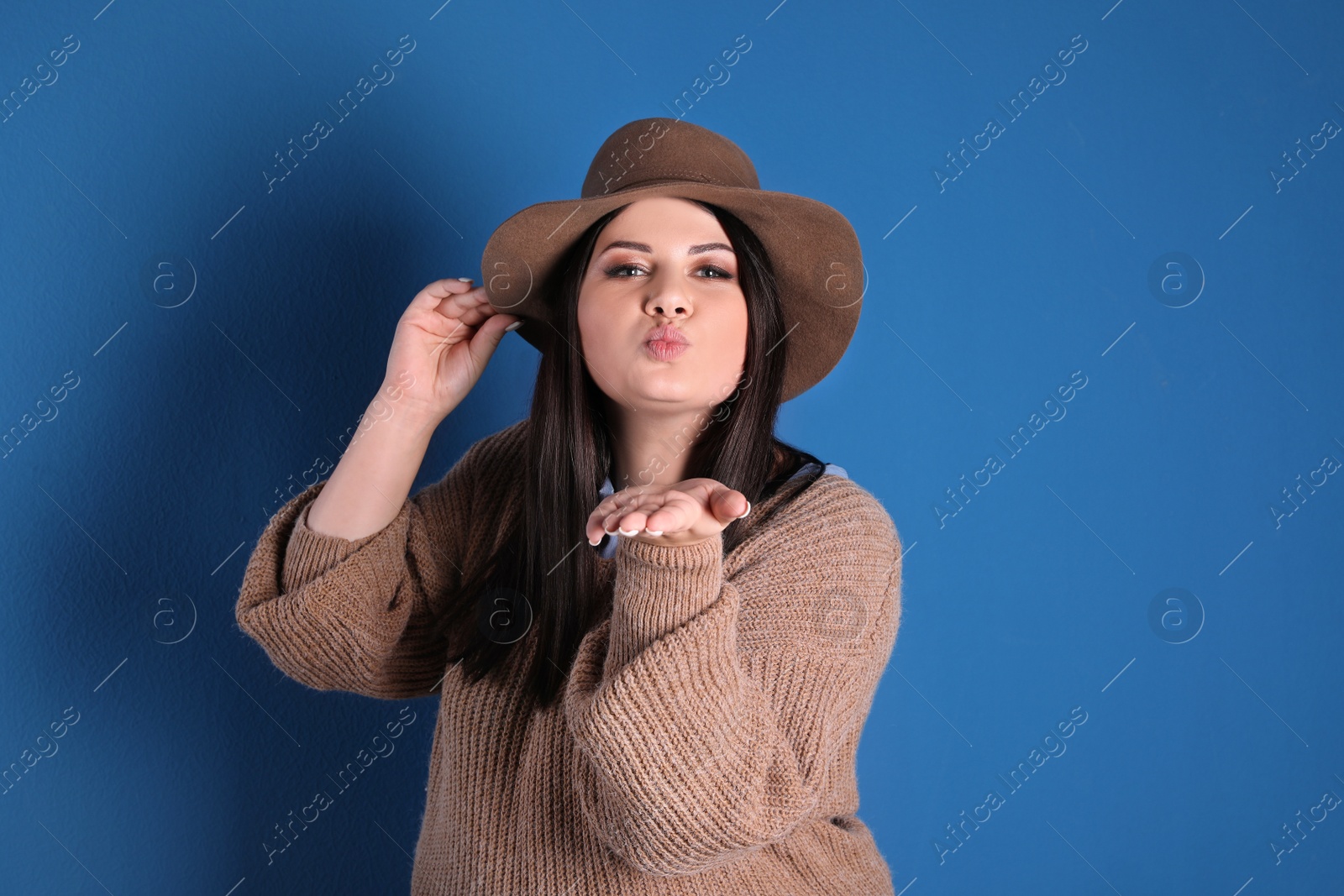 Photo of Beautiful overweight woman posing on blue background. Plus size model