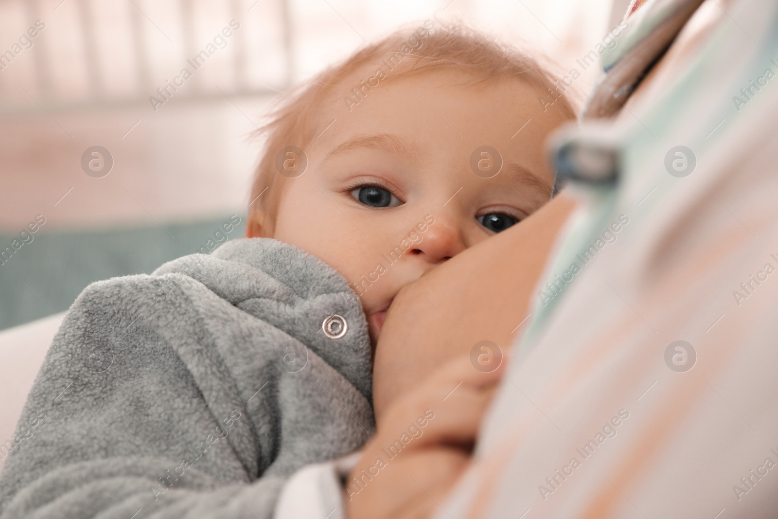 Photo of Woman breastfeeding her little baby at home, closeup