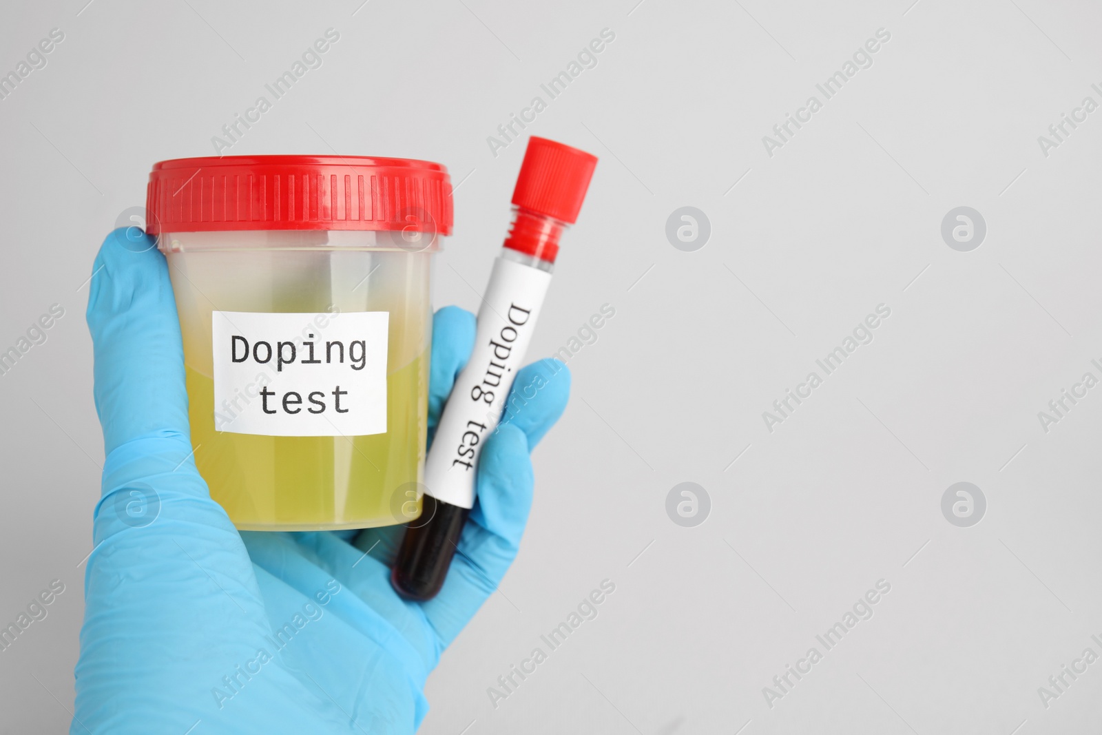 Photo of Closeup view of doctor holding jar and test tube with samples on light grey background, space for text. Doping control