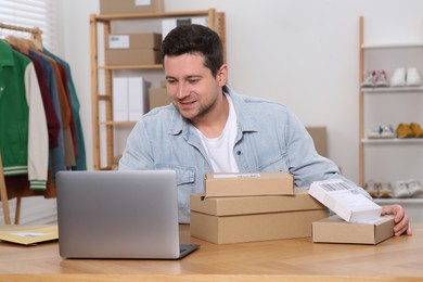 Photo of Seller with parcels and laptop working in office. Online store