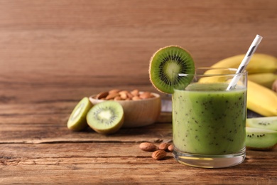 Photo of Delicious kiwi smoothie and ingredients on wooden table. Space for text