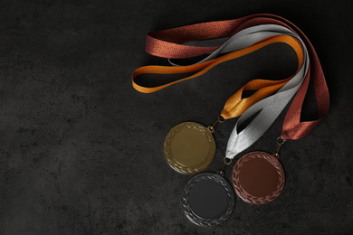 Gold, silver and bronze medals on grey stone background, flat lay. Space for design