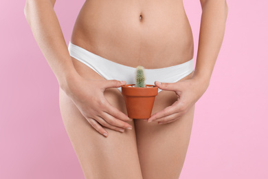 Photo of Woman with cactus showing smooth skin on pink background, closeup. Brazilian bikini epilation