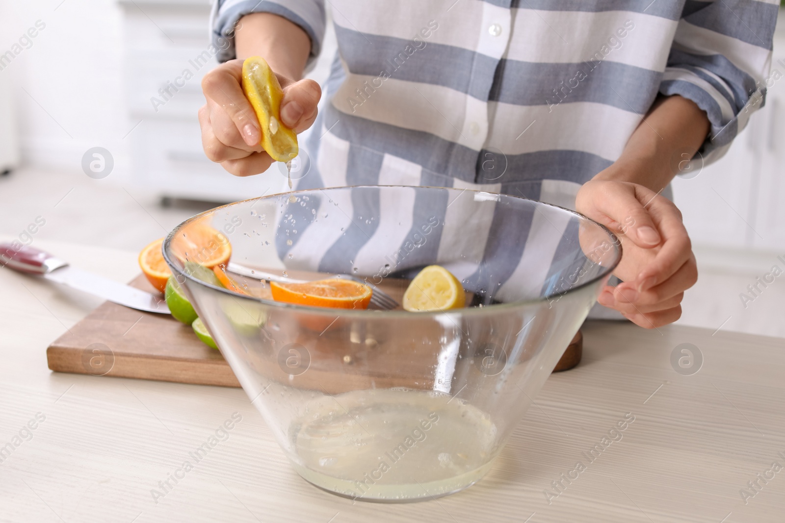 Photo of Young woman squeezing juice in bowl for lemonade on table, closeup. Natural detox drink