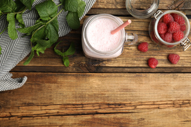 Photo of Tasty milk shake with raspberries and mint on wooden table, flat lay. Space for text