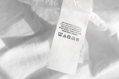 Photo of Clothing label in different languages on white garment, closeup