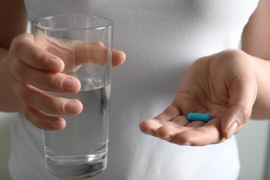 Photo of Woman holding glass of water and pill, closeup