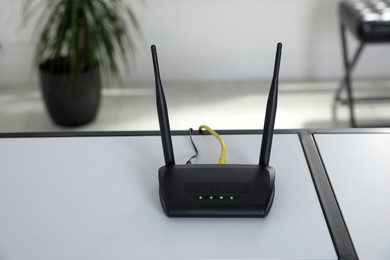 Photo of Modern Wi-Fi router on white table indoors