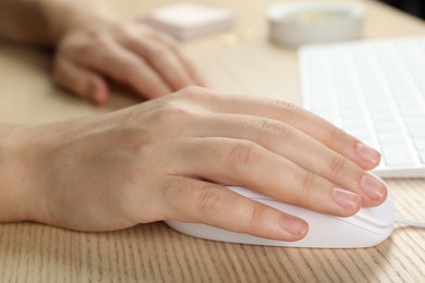 Photo of Woman using wired computer mouse at wooden table, closeup