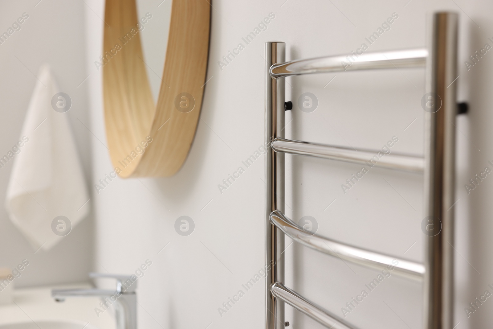 Photo of Heated towel rail on white wall in bathroom, closeup