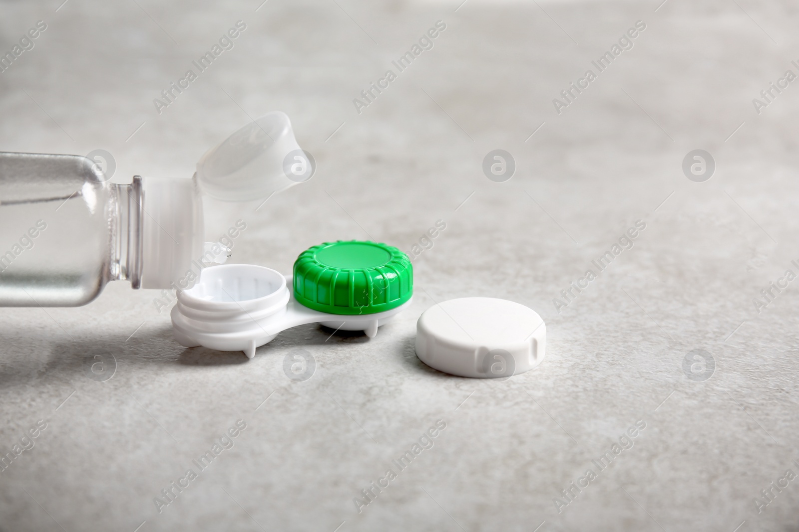 Photo of Dripping solution into contact lens case on light background