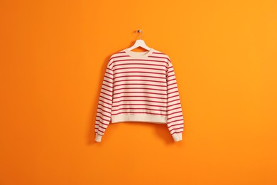 Photo of Hanger with striped sweatshirt on orange wall