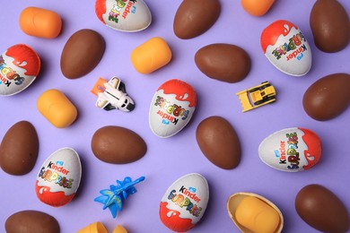 Sveti Vlas, Bulgaria - June 30, 2023: Kinder Surprise Eggs, toys and plastic capsules on violet background, flat lay