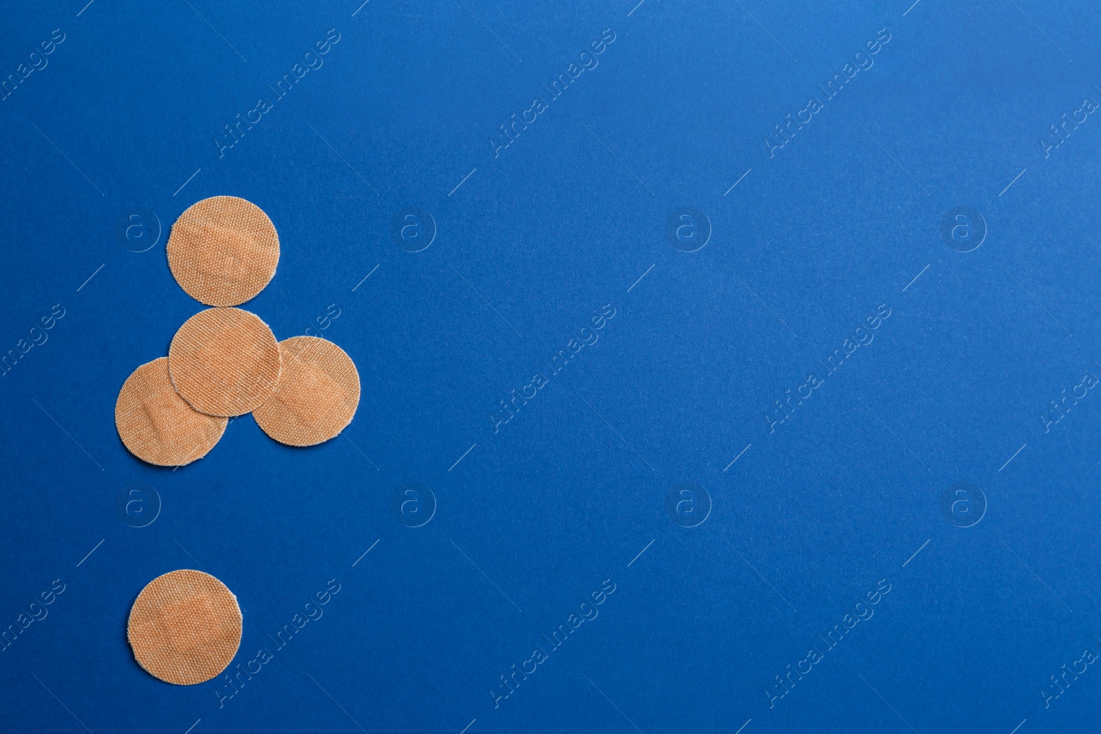 Photo of Sticking plasters on blue background, flat lay. Space for text