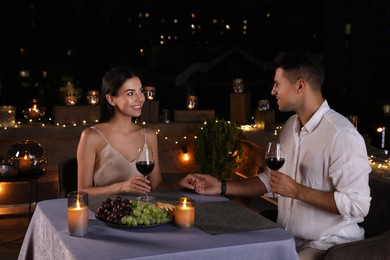 Romantic couple with glasses of red wine on cafe terrace at night
