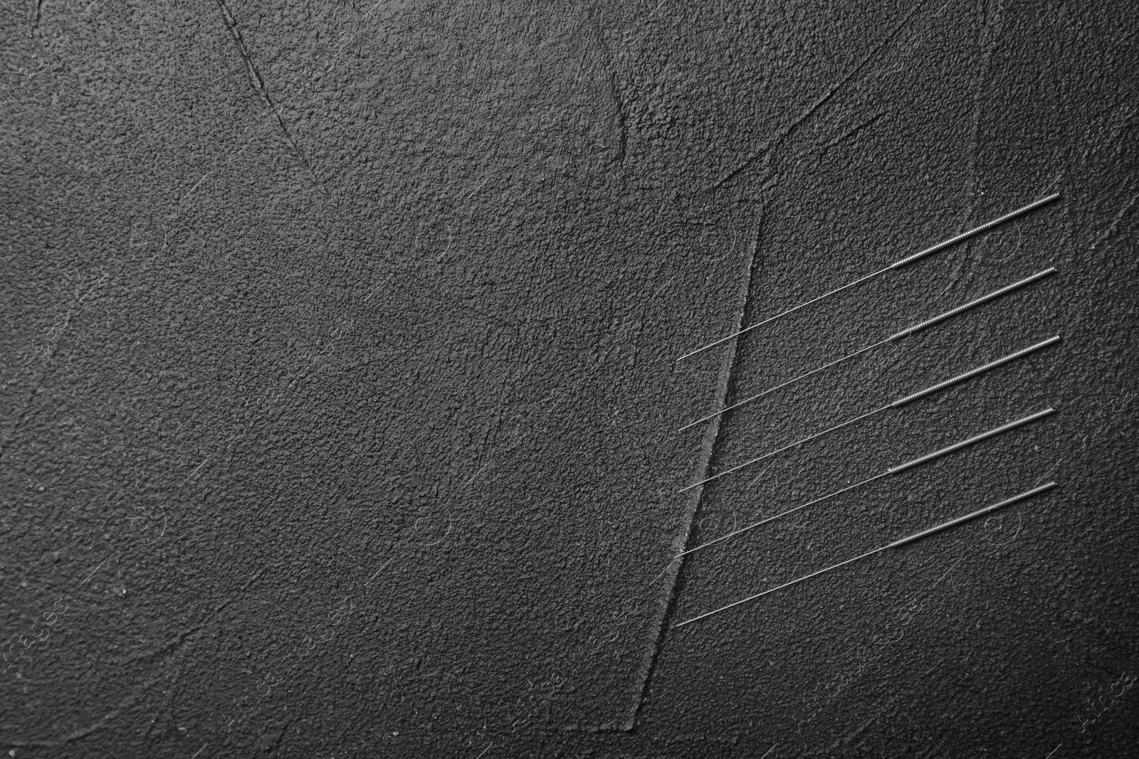 Photo of Needles for acupuncture on dark background, top view