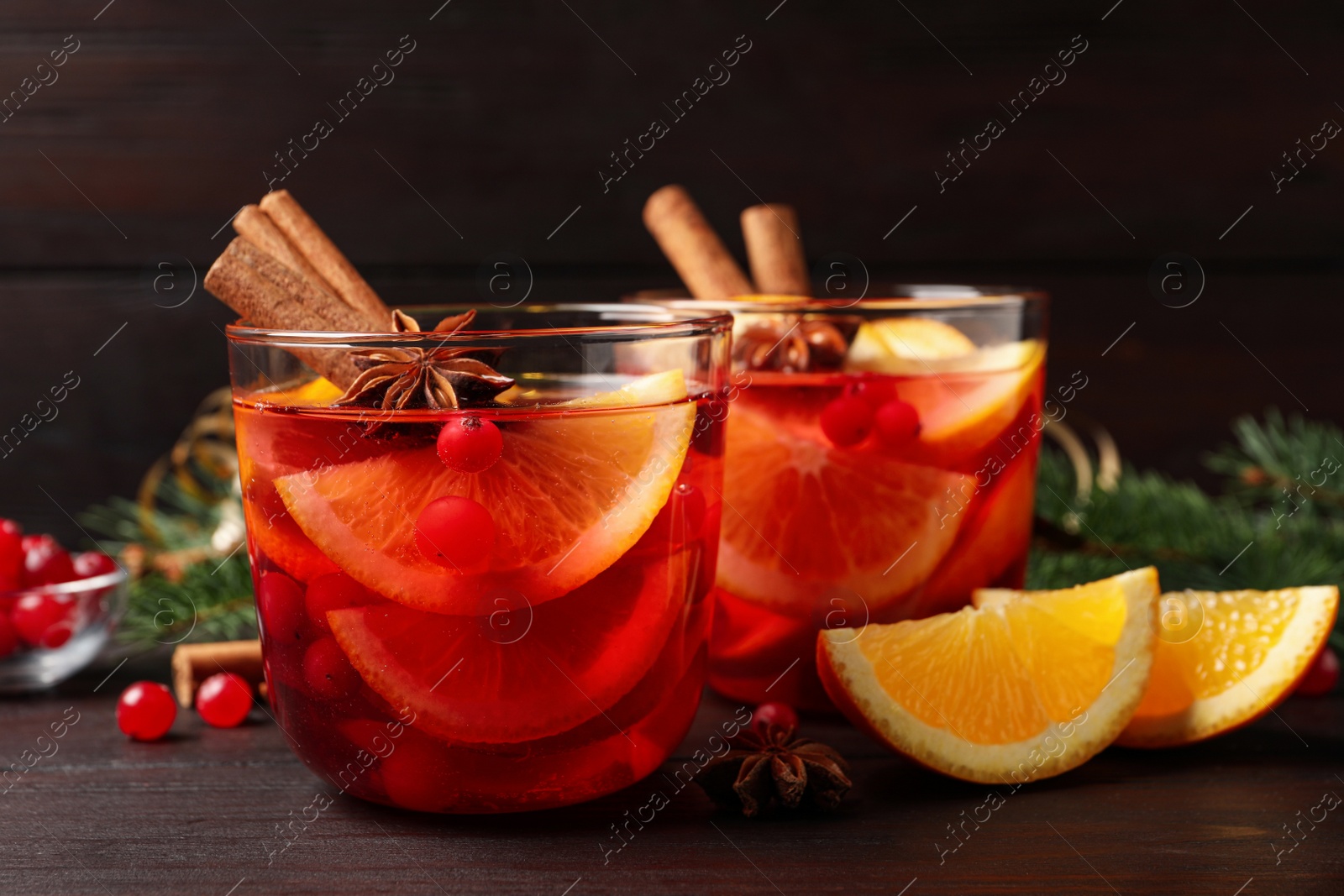 Photo of Delicious punch drink with cranberries, orange and spices on wooden table