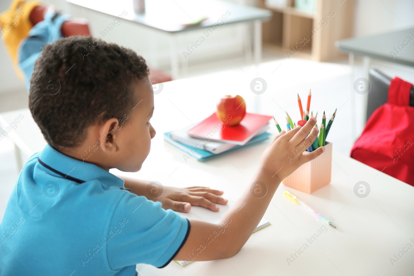 Photo of Cute little child doing assignment at desk in classroom. Elementary school