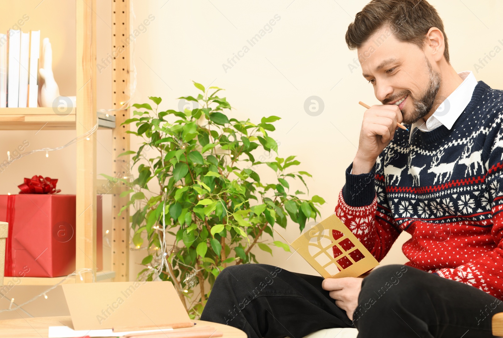 Photo of Happy man holding greeting card in living room