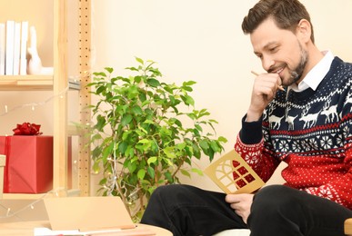 Photo of Happy man holding greeting card in living room