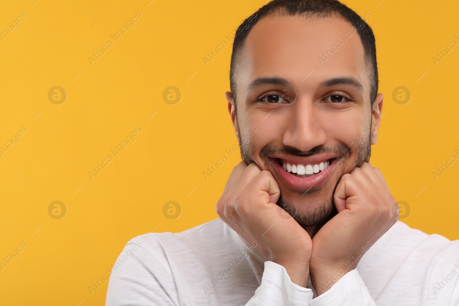 Photo of Portrait of smiling man with healthy clean teeth on orange background. Space for text