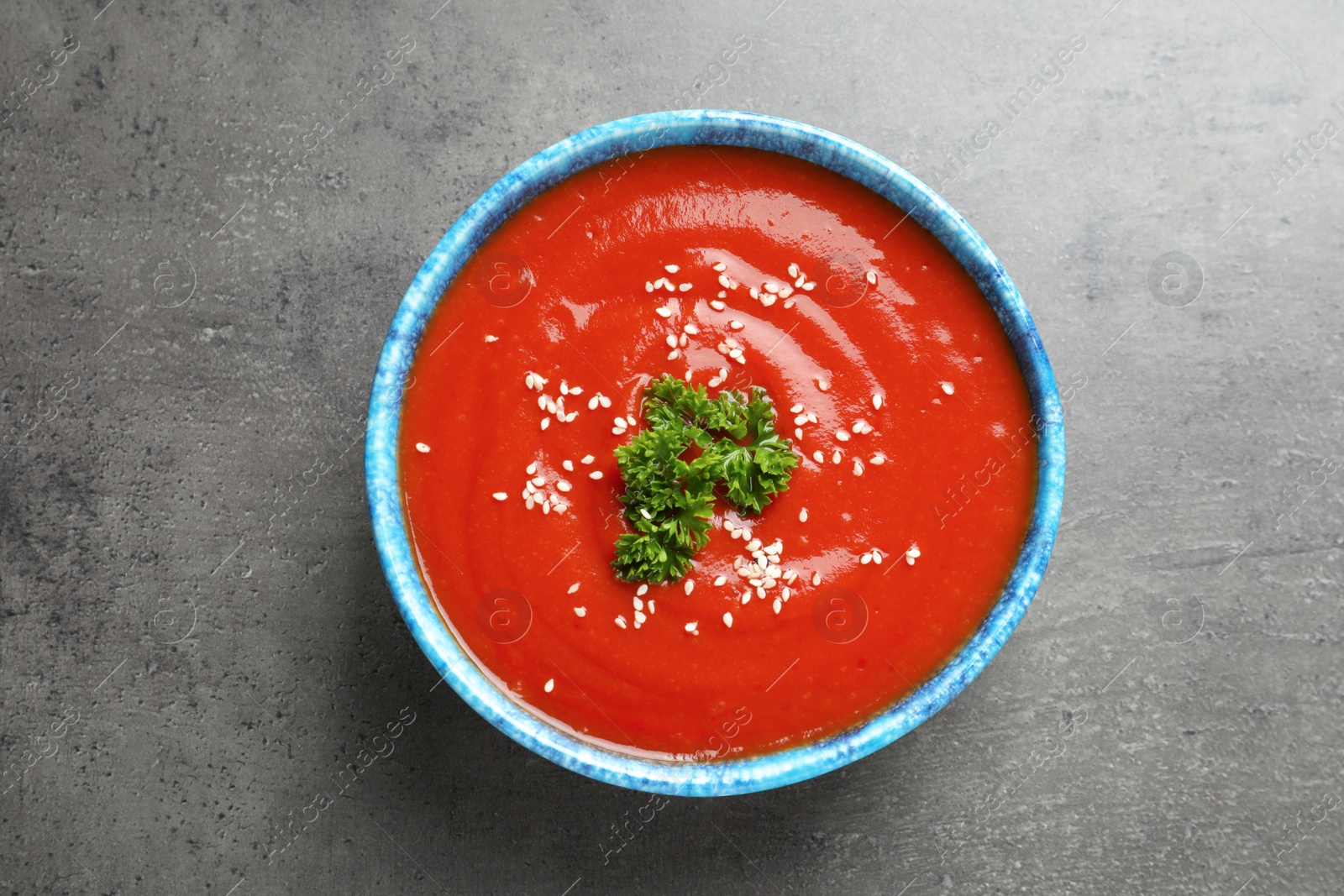 Photo of Bowl with fresh homemade tomato soup on grey background, top view