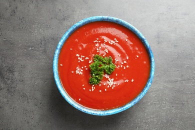 Bowl with fresh homemade tomato soup on grey background, top view