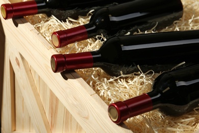 Photo of Wooden crate with bottles of wine, closeup