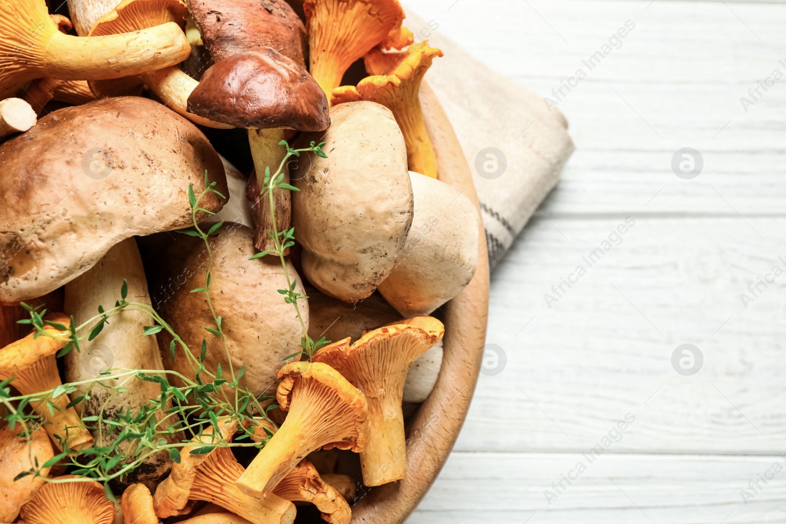 Photo of Different fresh wild mushrooms on white wooden table, closeup