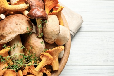 Photo of Different fresh wild mushrooms on white wooden table, closeup