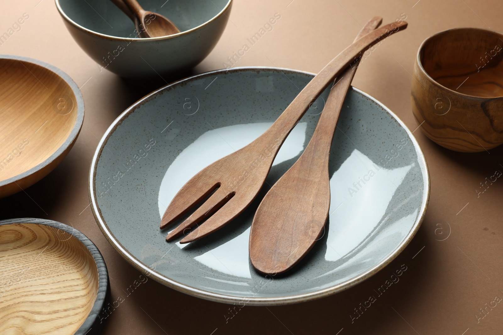 Photo of Stylish empty dishware and wooden cutlery on brown background