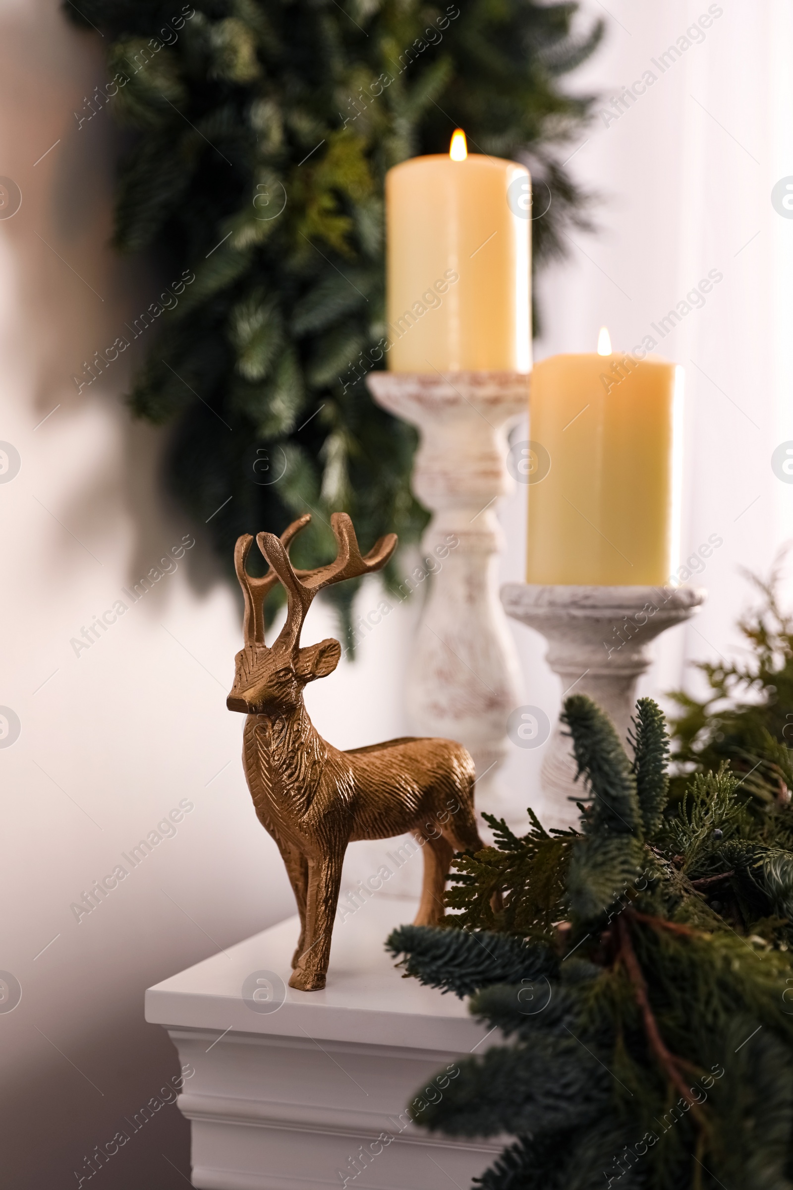 Photo of Christmas composition with decorative reindeer and candles near fir tree branches