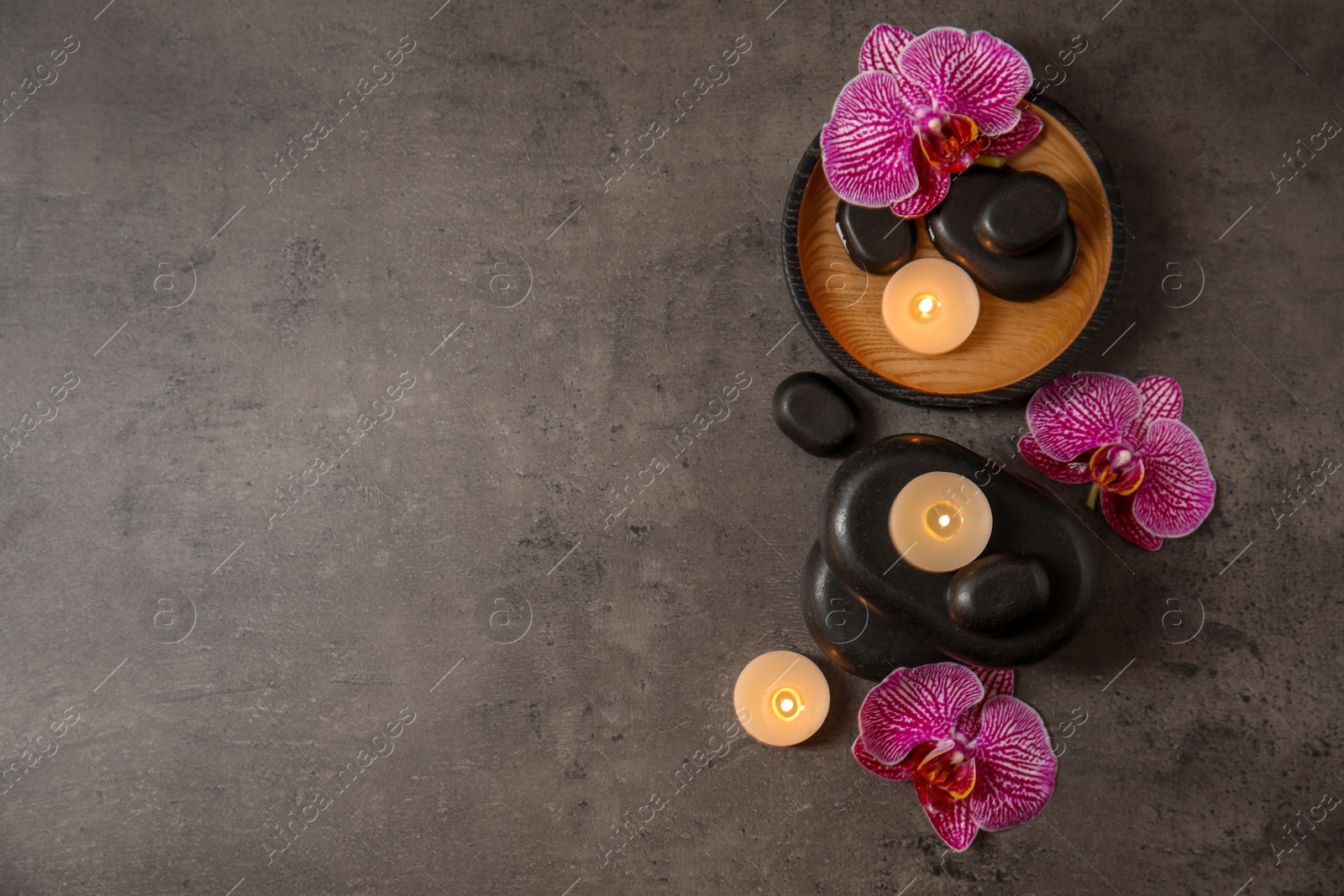 Photo of Flat lay composition with candles and spa stones on grey table. Space for text