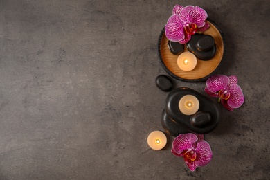 Photo of Flat lay composition with candles and spa stones on grey table. Space for text