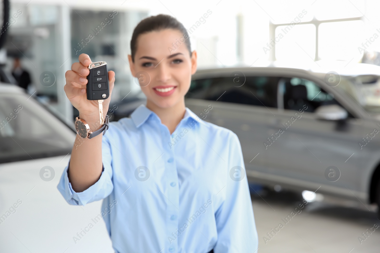 Photo of Young saleswoman with car key at workplace