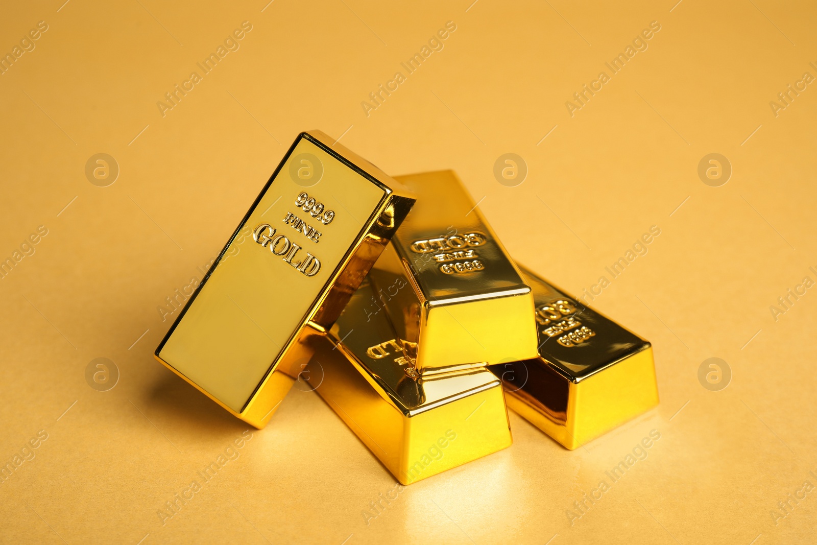 Photo of Many shiny gold bars on pale orange background