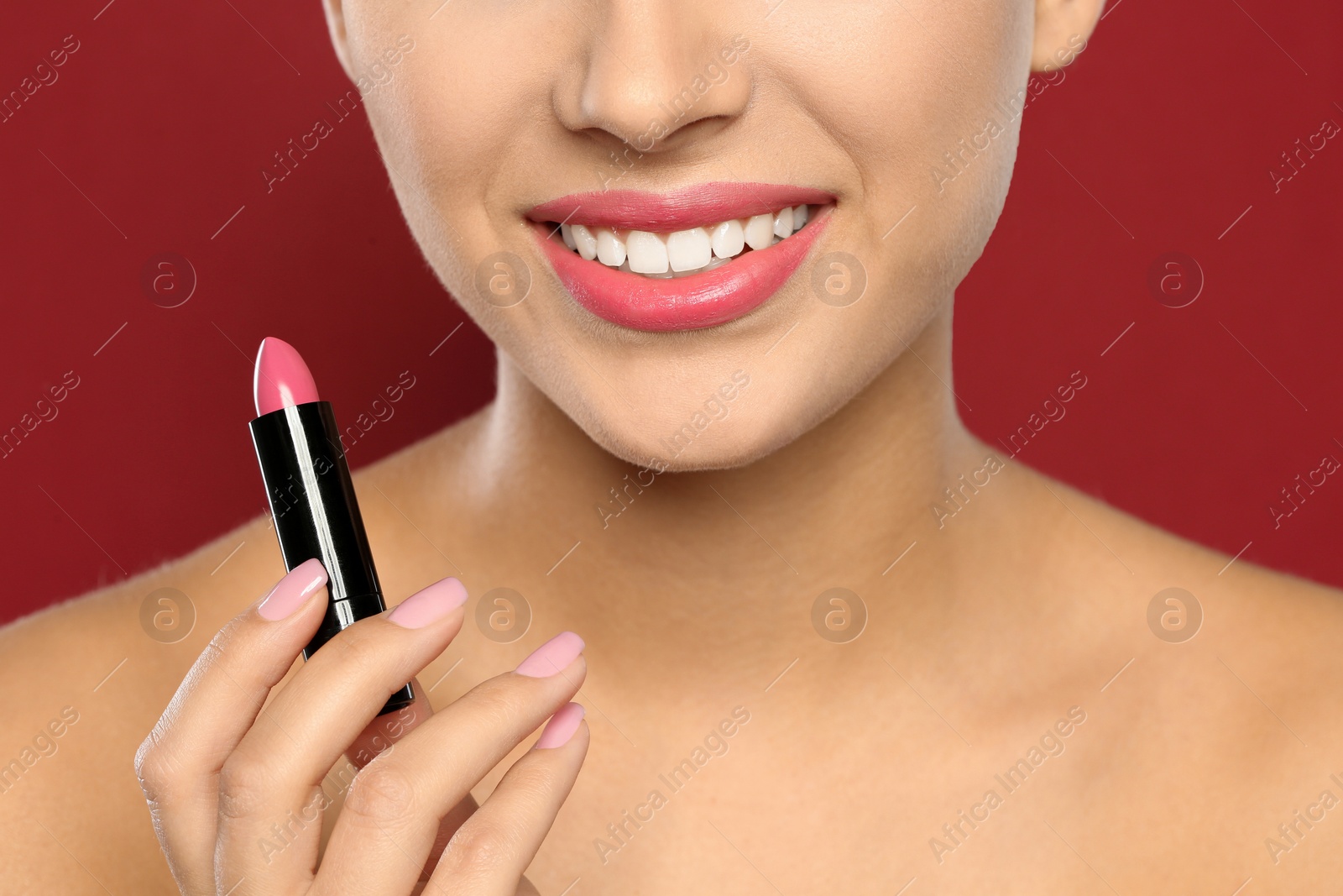 Photo of Young woman applying lipstick on color background, closeup