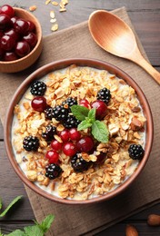 Photo of Bowl of muesli served with berries and milk on wooden table, flat lay