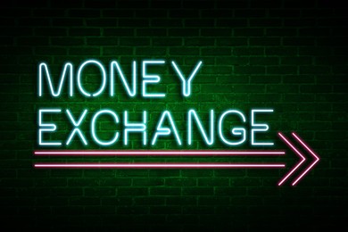 Image of Money Exchange neon sign on brick wall. Bright text and pink arrow